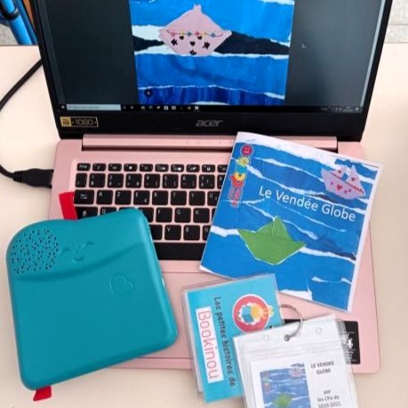 Bookinou ordinateur Matériel pédagogique Bookinou avec l’album posé devant un ordinateur.